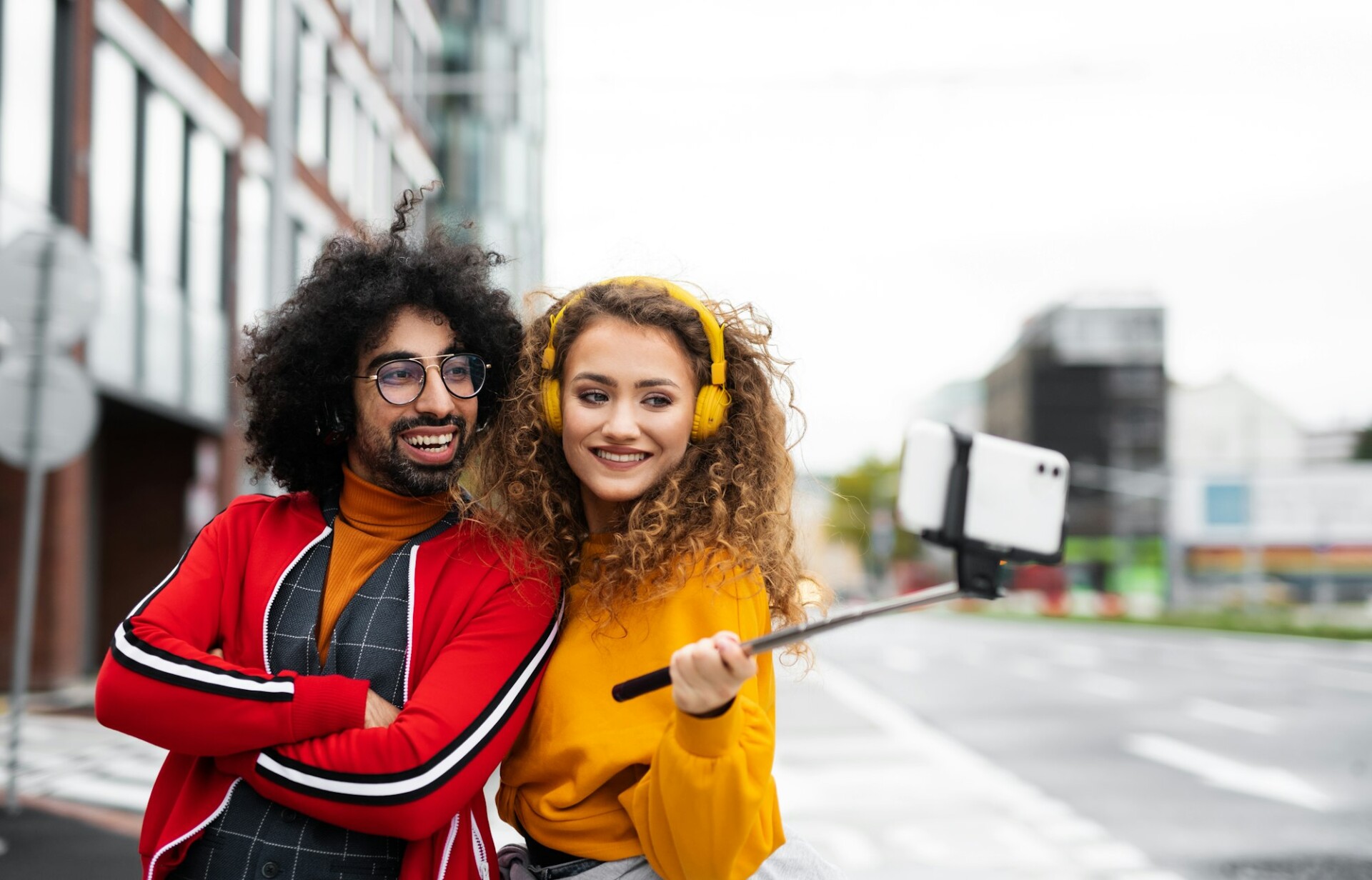 Young couple with smartphone making video outdoors on street, tik tok concept.