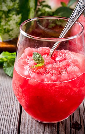 Summer fruit desserts, frozen cocktails. Ice cream granite from watermelon with mint, in portioned glasses, with slices of watermelon. On old rustic wooden table Copy space